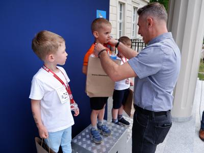 Dr Gerard Tomiak - burmistrz gm. Rakoniewice wręcza medal stojącemu na podeście chłopcu za zajęcie 1 miejsca w biegach. 