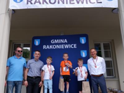 Zdjęcie grupowe chłopców na podium z Burmistrzem i Zastępcą Burmistrza gm. Rakoniewice oraz Przewodniczącym Rady Miejskiej.
