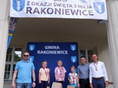 Zdjęcie grupowe dziewczyn na podium z Burmistrzem i Zastępcą Burmistrza gm. Rakoniewice oraz Przewodniczącym Rady Miejskiej.