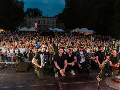 Kordian wraz z zespołem robiący zdjęcia z publicznością w tle