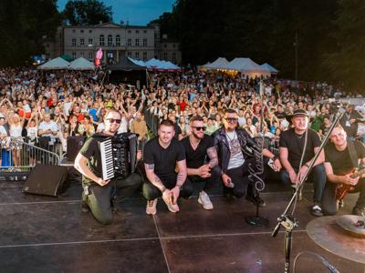 Kordian wraz z zespołem robiący zdjęcia z publicznością w tle