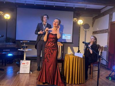 śpiewaczka w bordowej sukni a za nią paderewski