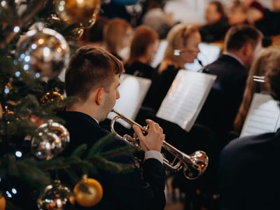 Mężczyzna grający na trąbce zza choinki