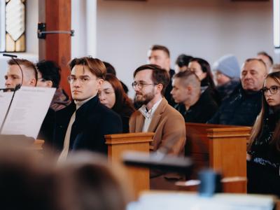 Publiczność siedząca w ławkach w kościele