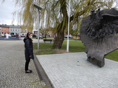 Dyrektor Rakoniewickiego Ośrodka Kultury Gizela Ziółkowska patrzy stojąc na Pomnik Pamięci i Wolności w Rakoniewicach