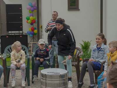 Dzieci i kobieta w siedzące w kręgu i grające na bębenkach.