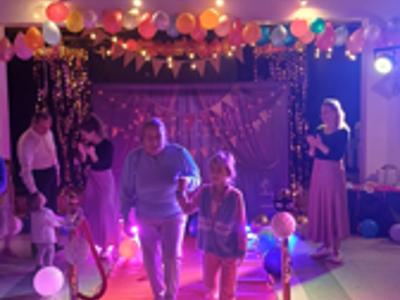 Babcia i wnuczka wchodzą na scenę – Starsza kobieta w błękitnej bluzie trzyma za rękę uśmiechniętą dziewczynkę