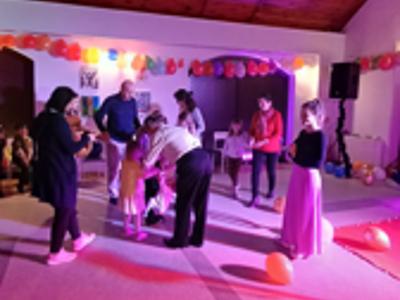 Magiczny finał wydarzenia – Wszyscy uczestnicy w tańcu i śmiechu kończą wspólną zabawę, otoczeni kolorowymi światłami, balonami i atmosferą radości.