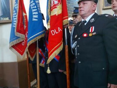 Mężczyźni w mundurach strażackich z horągwiami.