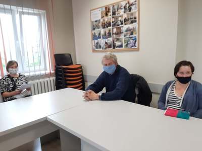 Na zdjęciu znajdują się trzy osoby siedzące przy stole. Wszyscy mają na twarzy maseczki.