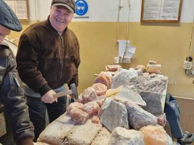 Fotografia przedstawia dwóch seniorów rozbijających bryły soli.