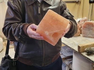 Na zdjęciu starszy mężczyzna eksponuje wyszlifowaną bryłę soli.