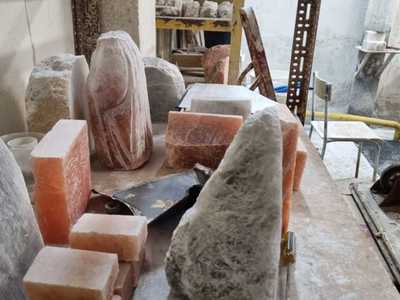 Fotografia przedstawia wnętrze pracowni rzeźbiarskiej. Na stole duże bryły soli w różnych kolorach.