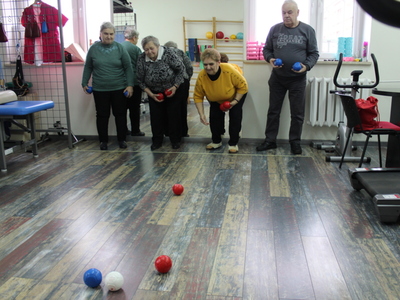 Na zdjęciu widać czwórkę seniorów grających w bocce na sali rehabilitacyjnej.