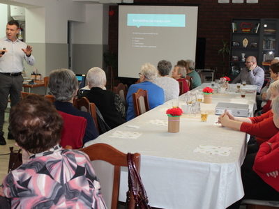 Na zdjęciu wykładowca tłumaczy seniorom definicje rehabilitacji medycznej.