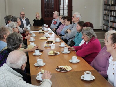 Na fotografii widać grupę słuchaczy siedzącą przy wspólnym stole i słuchającą wykładu.