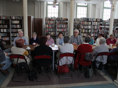 Na zdjęciu grupa słuchaczy wykładu. W tle regały z książkami.