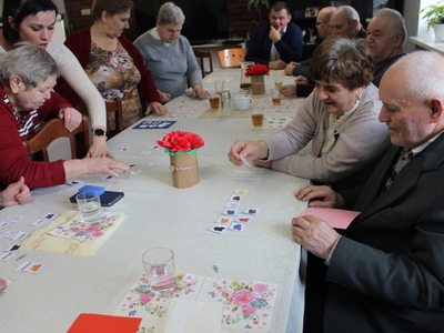Zdjęcie przedstawia seniorów siedzących przy stole i układających kolory oraz ich nazwy w języku angielskim.