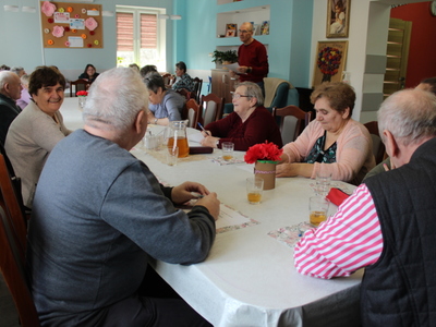 Zdjęcie wykonane w sali głównej Domu Dziennego Pobytu Senior+ w Sompolnie. Przedstawia uczestników zajęć podczas quizu na temat kobiet i mężczyzn.