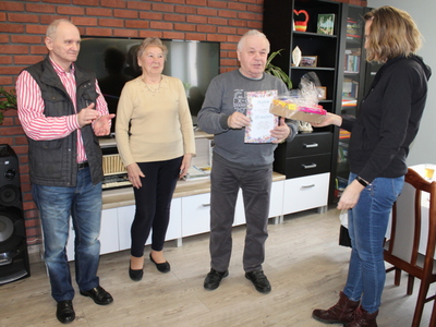 Fotografia przedstawia opiekunkę osób starszych wręczającą dyplomy i upominki laureatom quizu.