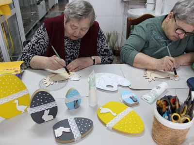 Zdjęcie przedstawia dwie starsze panie malujące figurki wielkanocne.