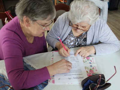 Fotografia przedstawia dwie seniorki wypełniające zadanie wspomagające pamięć i koncentrację osób starszych.