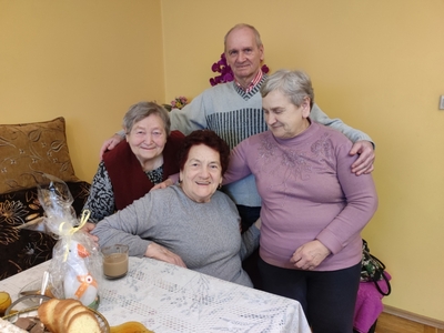 Zdjęcie wykonane w domu jednej z byłych uczestniczek Domu Dziennego Pobytu Senior+ w Sompolnie. Przedstawia czwórkę seniorów siedzących przy stole.