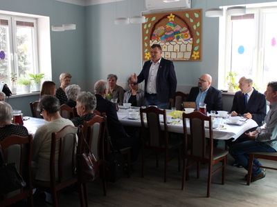 Na zdjęciu widać burmistrza miasta Sompolna, który przemawia do wszystkich w pozycji stojącej. Pozostali uczestnicy spotkania siedzą przy stołach.