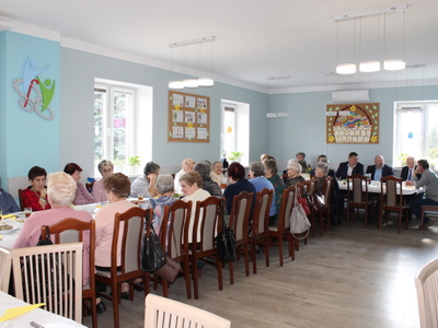 Fotografia przedstawia salę główną DDP i wszystkich uczestników spotkania siedzących przy stołach. W tle logo DDP i dwie gazetki wielkanocne.