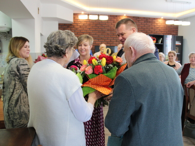 Na zdjęciu przedstawiciele samorządu miasta Sompolna składają życzenia i wręczają bukiet jubilatce. W tle pracownicy DDP i seniorzy.