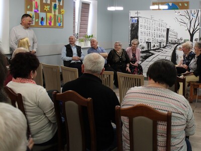 Zdjęcie przedstawia burmistrza miasta Sompolna komentującego przedstawienie, roześmianych seniorów oraz widownię.