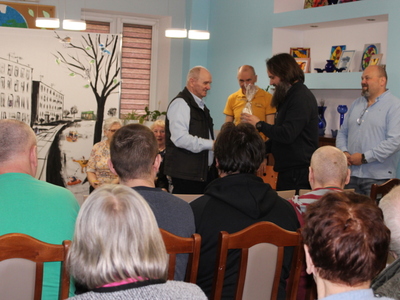 Na zdjęciu jeden z gości wręcza seniorowi symboliczny upominek.