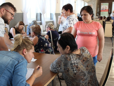 4)	Na zdjęciu kobieta pobierająca kopertę życia u pracowników socjalnych