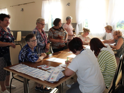 5)	Fotografia przedstawia grupę seniorów pobierających koperty życia od pracowników MGOPS w Sompolnie