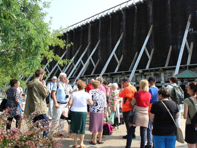 1)	Zdjęcie wykonane pod tężniami w Ciechocinku. Widać na nim grupę osób w różnym wieku biorących udział w wycieczce.