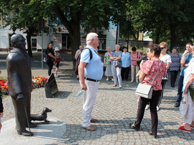2)	Na zdjęciu widać grupę osób w różnym wieku biorących udział w wycieczce do Ciechocinka. W centralnym miejscu mężczyzna – przewodnik, a z lewej strony pomnik Jerzego Waldorffa.