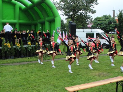 13)	Na zdjęciu tańczące Mażoretki oraz Sompoleńska Orkiestra Dęta na scenie.