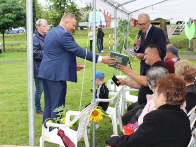 6)	Zdjęcie przedstawia burmistrza wręczającego nagrodę jednemu z mieszkańców.