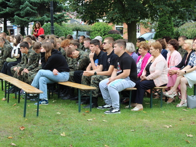 Na fotografii młodzież, seniorzy oraz bibliotekarki słuchający fragmentu lektury.