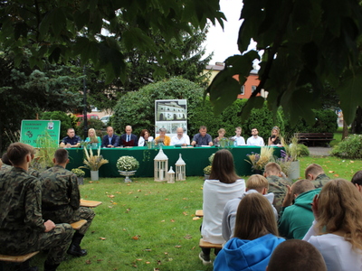 Zdjęcie przedstawia lektorów oraz audytorium podczas narodowego czytania w parku.