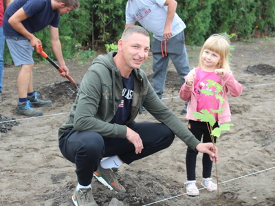 Na zdjęciu mężczyzna z córką dumnie prezentują posadzone drzewo.