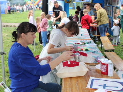 Zdjęcie przedstawia kobietę i jej córkę malującą torby podczas zajęć warsztatowych.