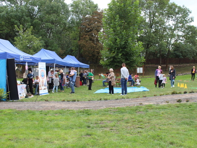 Na fotografii stoisko MGOPS oraz miejsca, gdzie odbywały się zajęcia warsztatowe. Po prawej stronie animacje dla dzieci oraz uczestnicy pikniku.