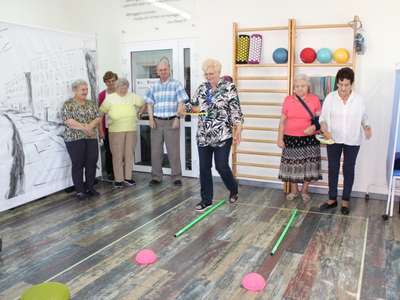 Na zdjęciu seniorzy ścigający się w torze przeszkód z jabłkiem na rakietce do badmintona.