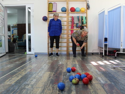 Fotografia przedstawia dwie kobiety grające w bocce do jabłka.