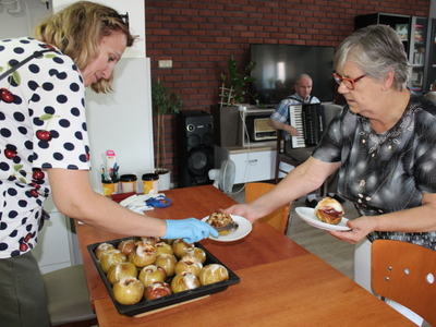 Na zdjęciu instruktorka zajęć kulinarnych nakłada pieczone jabłka na talerze.