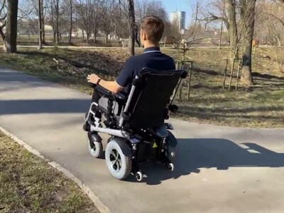 Zdjęcie przedstawia mężczyznę jadącego na wózku inwalidzkim