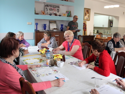 Zdjęcie przedstawia seniorów siedzących przy stole i rozwiązujących quiz o Sompolnie.