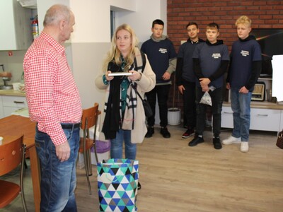 Na zdjęciu nauczycielka wręczająca przedstawicielowi seniorów podarunki od dzieci z przedszkola w Mąkolnie.