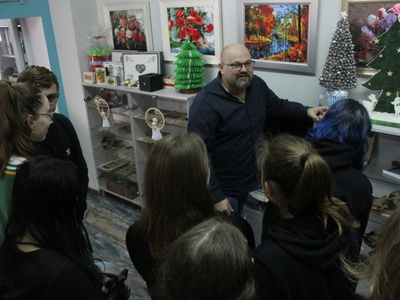 Zdjęcie przedstawia Dyrektora MGOPS w Sompolnie, który pokazuje młodzieży przedmioty w gablocie antykami.